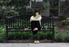 A music student visiting from Korea reads notes while relaxing on a bench at the U-M Law Quad.