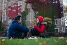 Students visit on a lawn in front of the law quad.