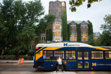 A student catches a ride on a new campus hybrid bus as it stops in front of Michigan Union.